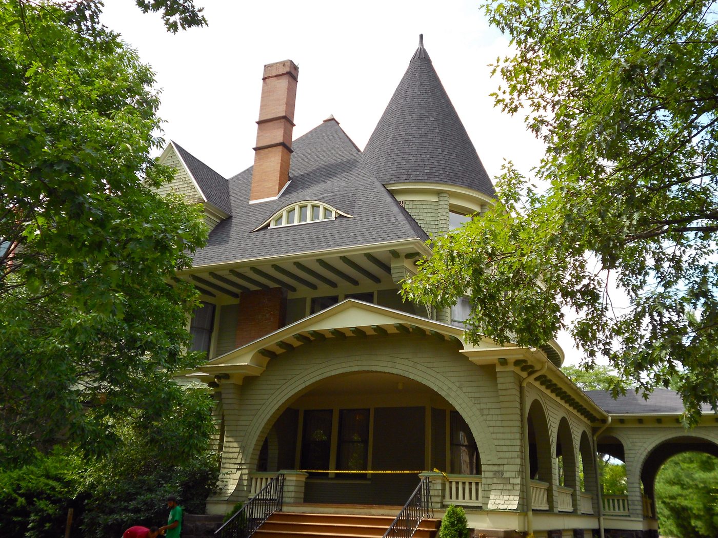 A large Victorian house with a covered porch on a residential street
