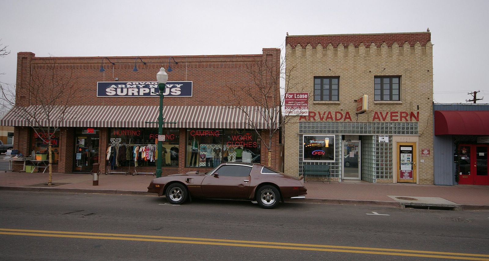 Historic brick storefronts including a tavern and surplus store on a street in Olde Town Arvada