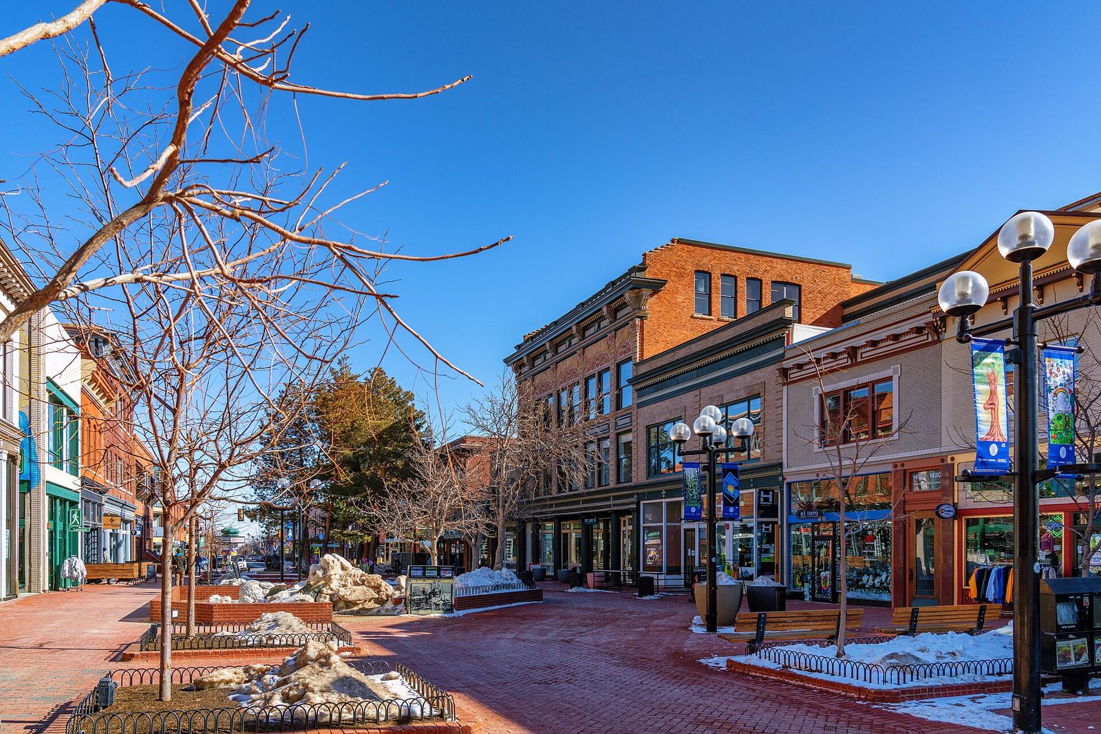 Pearl Street in downtown Boulder on a sunny winter day with brick storefronts and patches of snow