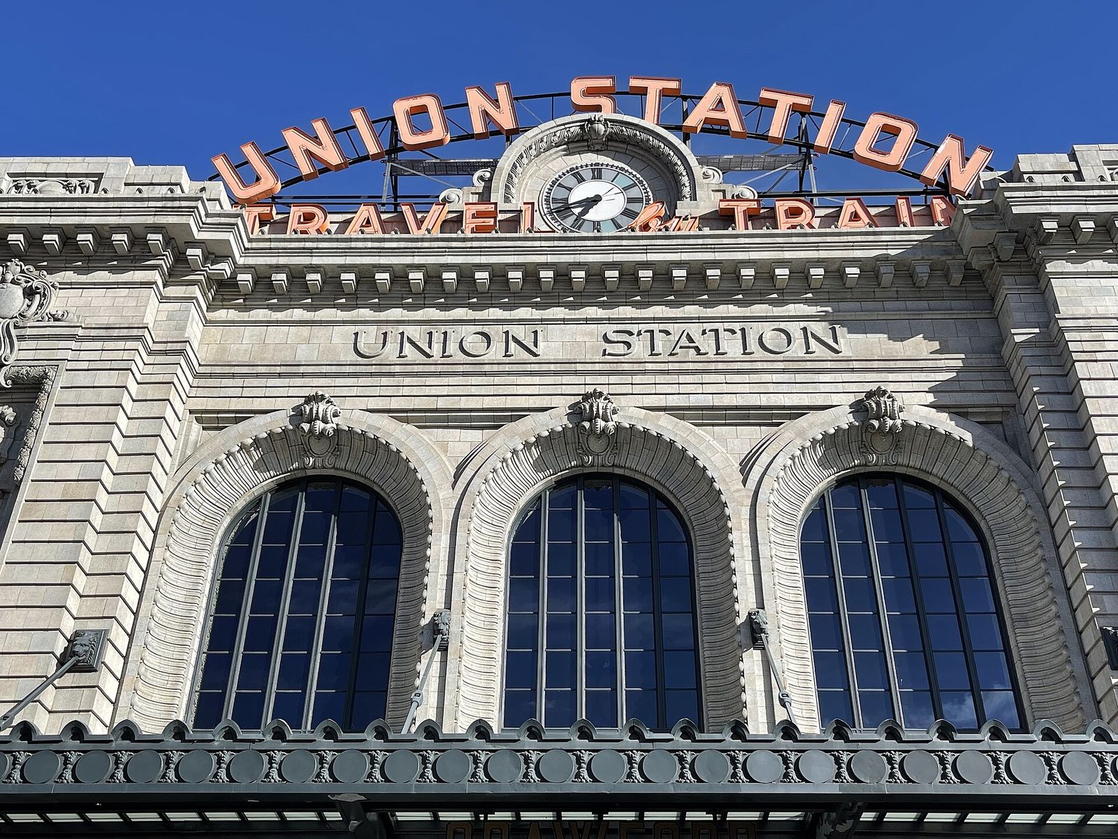 Front of Denver Union Station with its Travel by Train neon sign and arched windows
