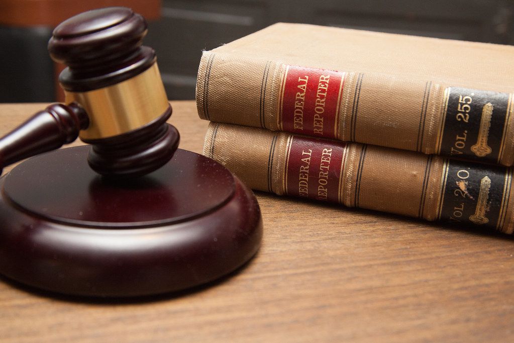 Wooden judge's gavel resting beside old leather-bound law books