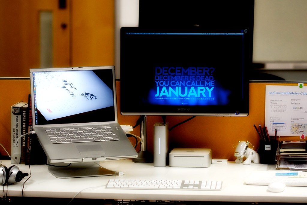 Home office desk with a laptop and a monitor showing a January calendar graphic