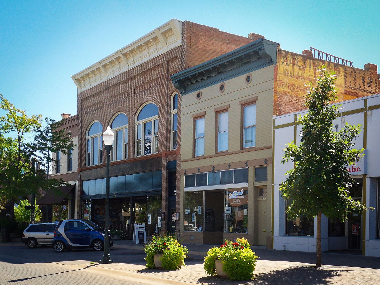 Restored brick storefronts with arched windows and planters in downtown Greeley