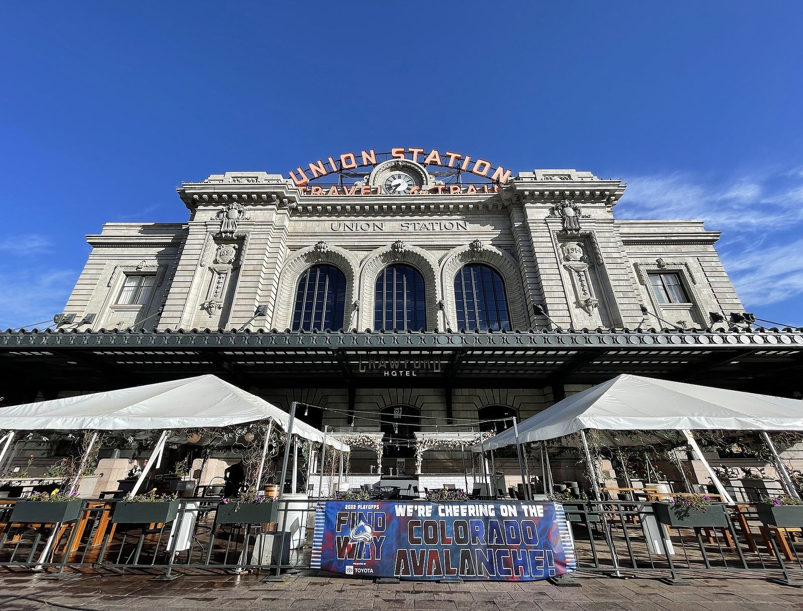 Denver Union Station facade with its Travel by Train sign and patio umbrellas