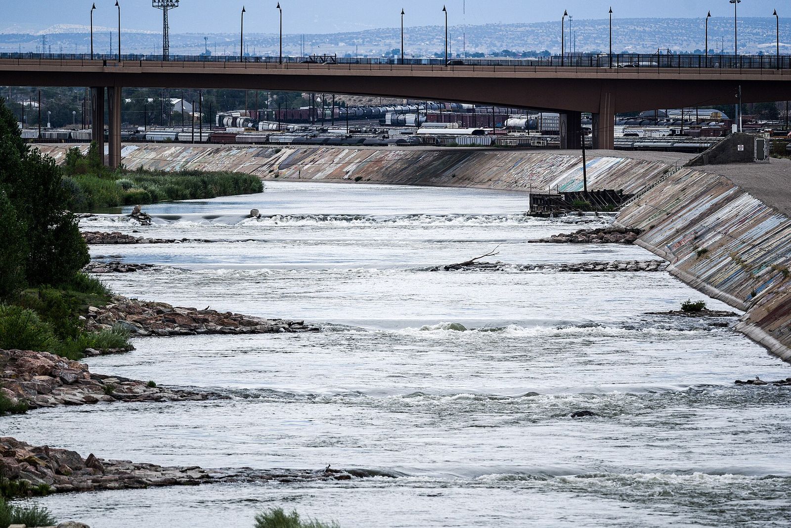 Whitewater park on the Arkansas River in Pueblo with water rushing over concrete drops below a bridge
