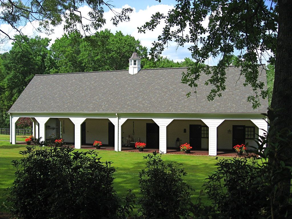 White stable building with arched stalls and a cupola on a green Aiken lawn