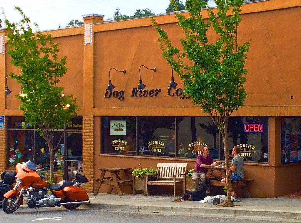 Orange-painted cafe storefront with outdoor tables and motorcycles parked in front