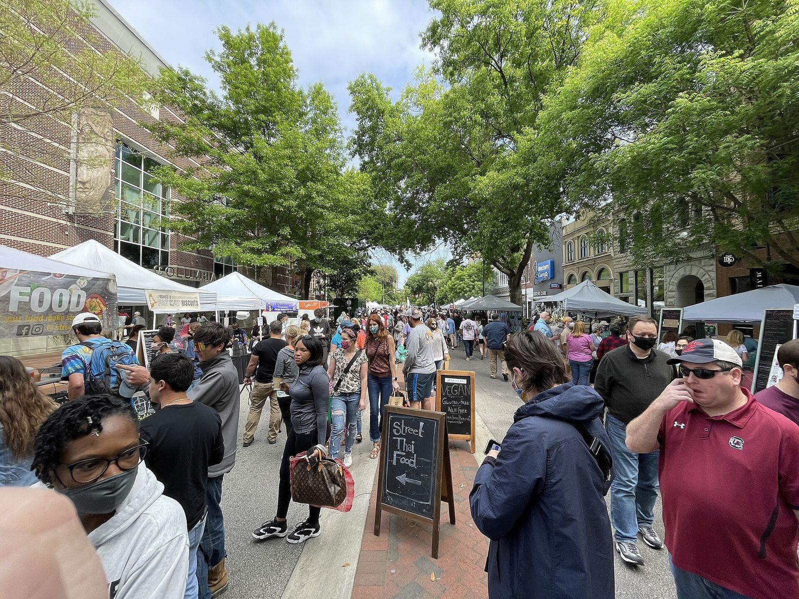 Crowds walking between vendor tents at the Soda City Market on Main Street in Columbia