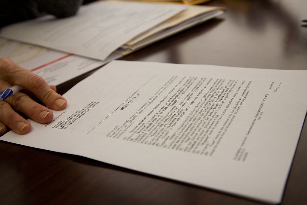 Printed pages spread on a table with a hand resting beside them
