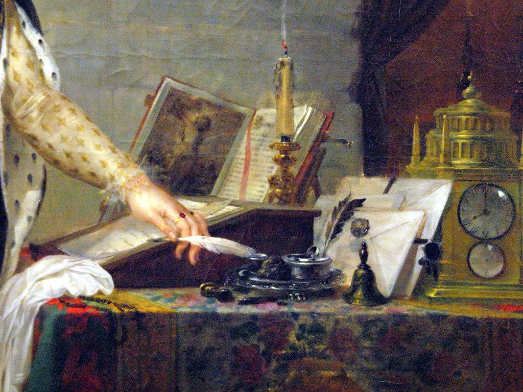 Painting of a hand writing a letter with a quill beside an inkwell and papers on a desk