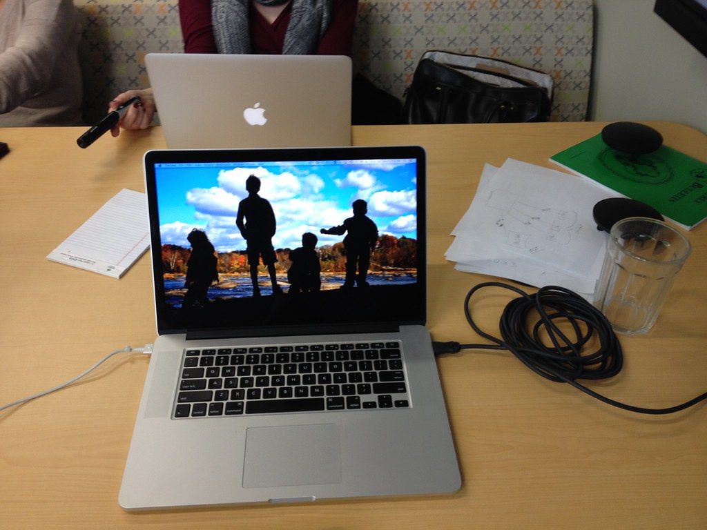 Open laptop on a cluttered desk beside papers and cables