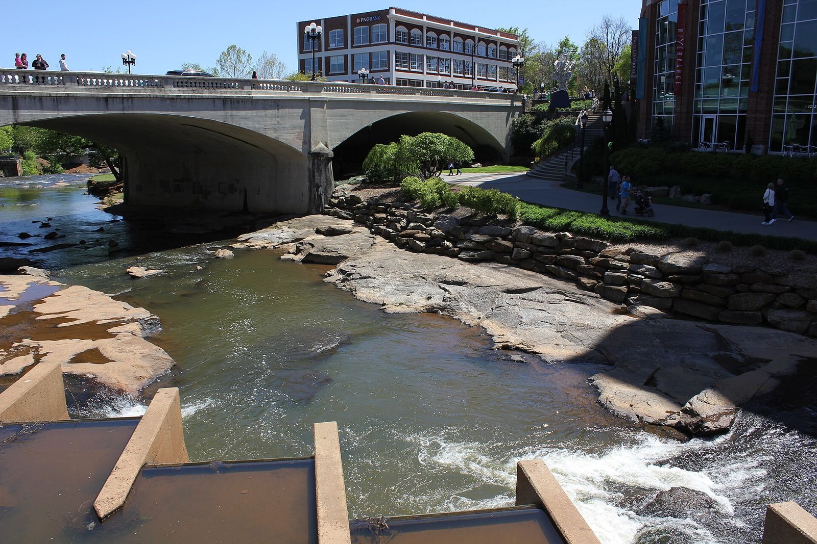 Main Street Bridge crossing the Reedy River in downtown Greenville with tall buildings behind
