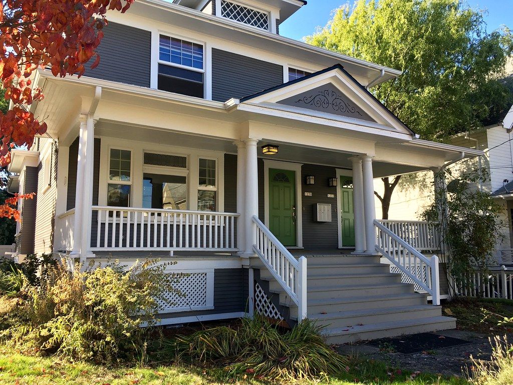 Blue duplex porch with two front doors, railings and potted plants