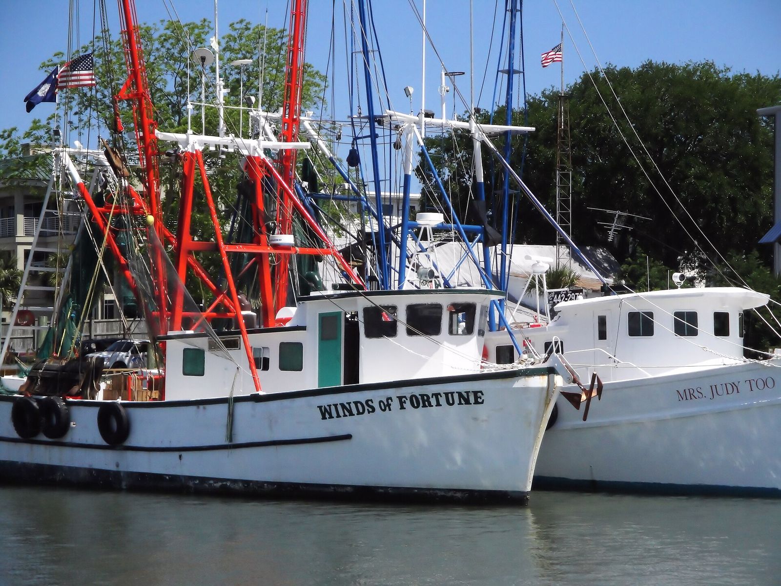 Shrimp boats with red and white rigging docked on Shem Creek