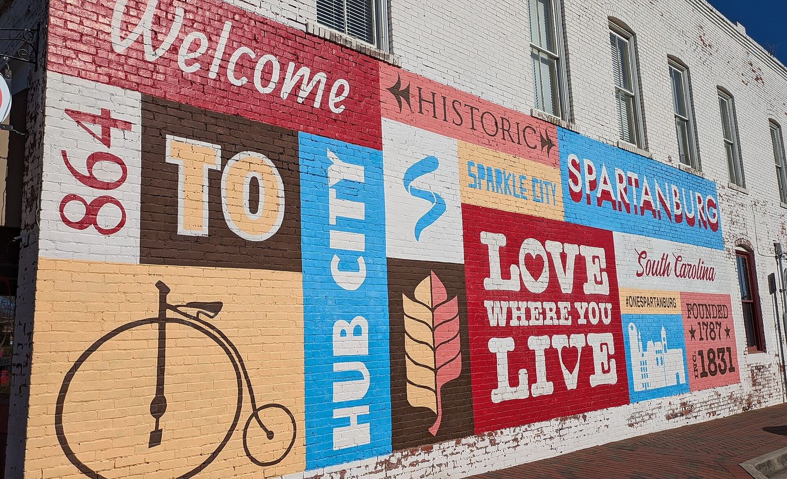 Colorful Love Where You Live mural with a penny-farthing bicycle on a downtown Spartanburg wall