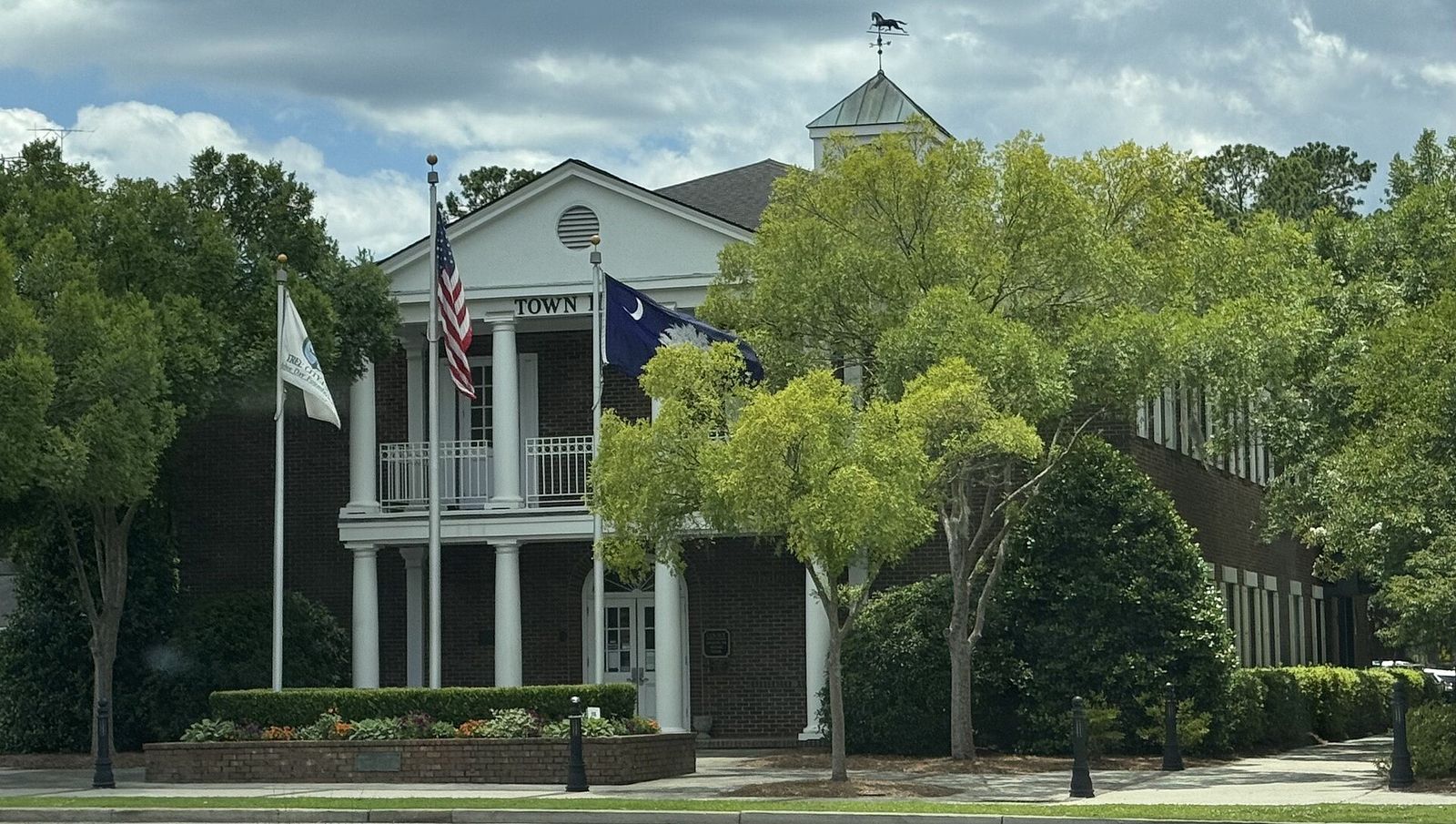 White-columned Summerville Town Hall behind trees and flags