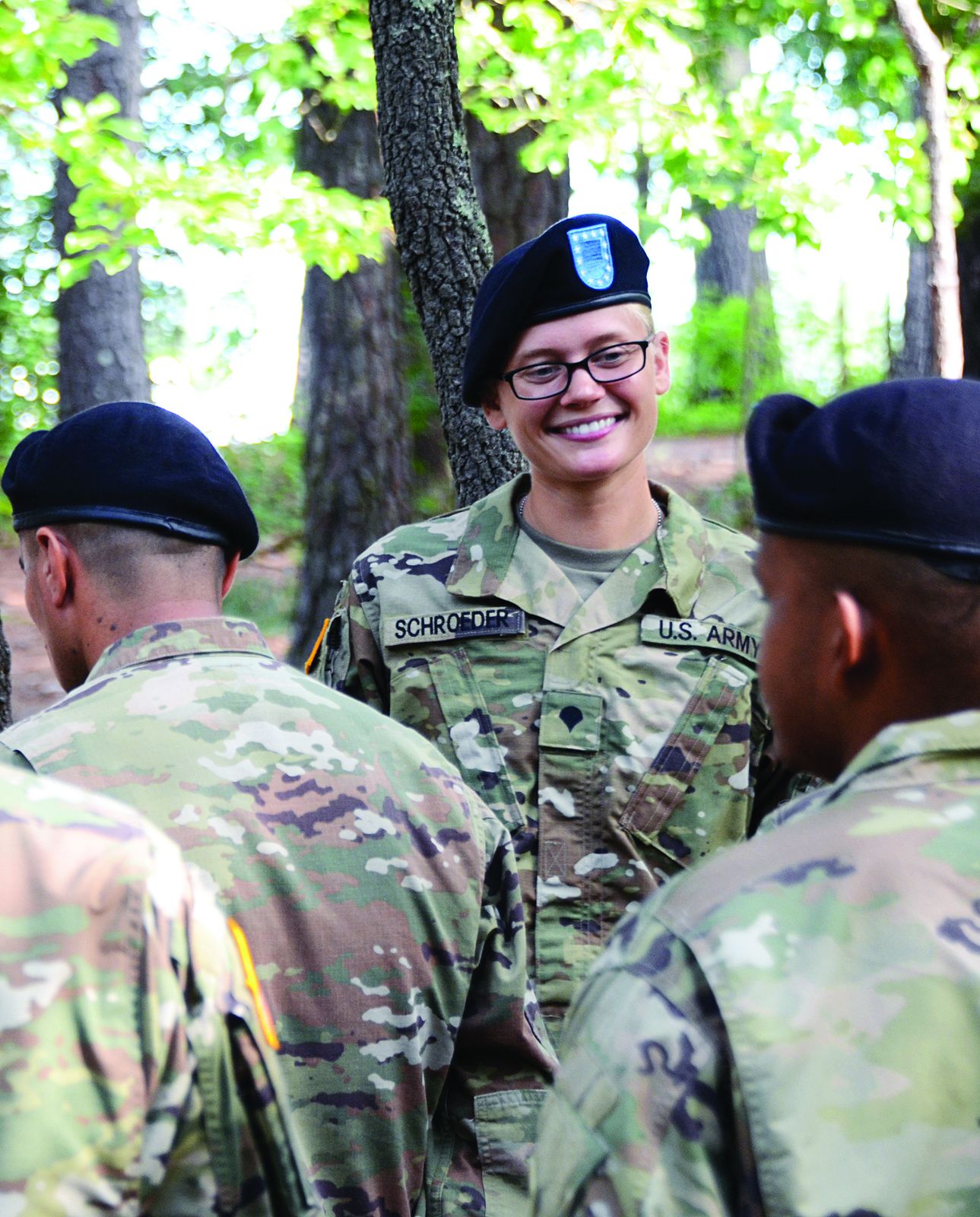 Smiling soldier in a beret among fellow soldiers after basic combat training graduation at Fort Jackson