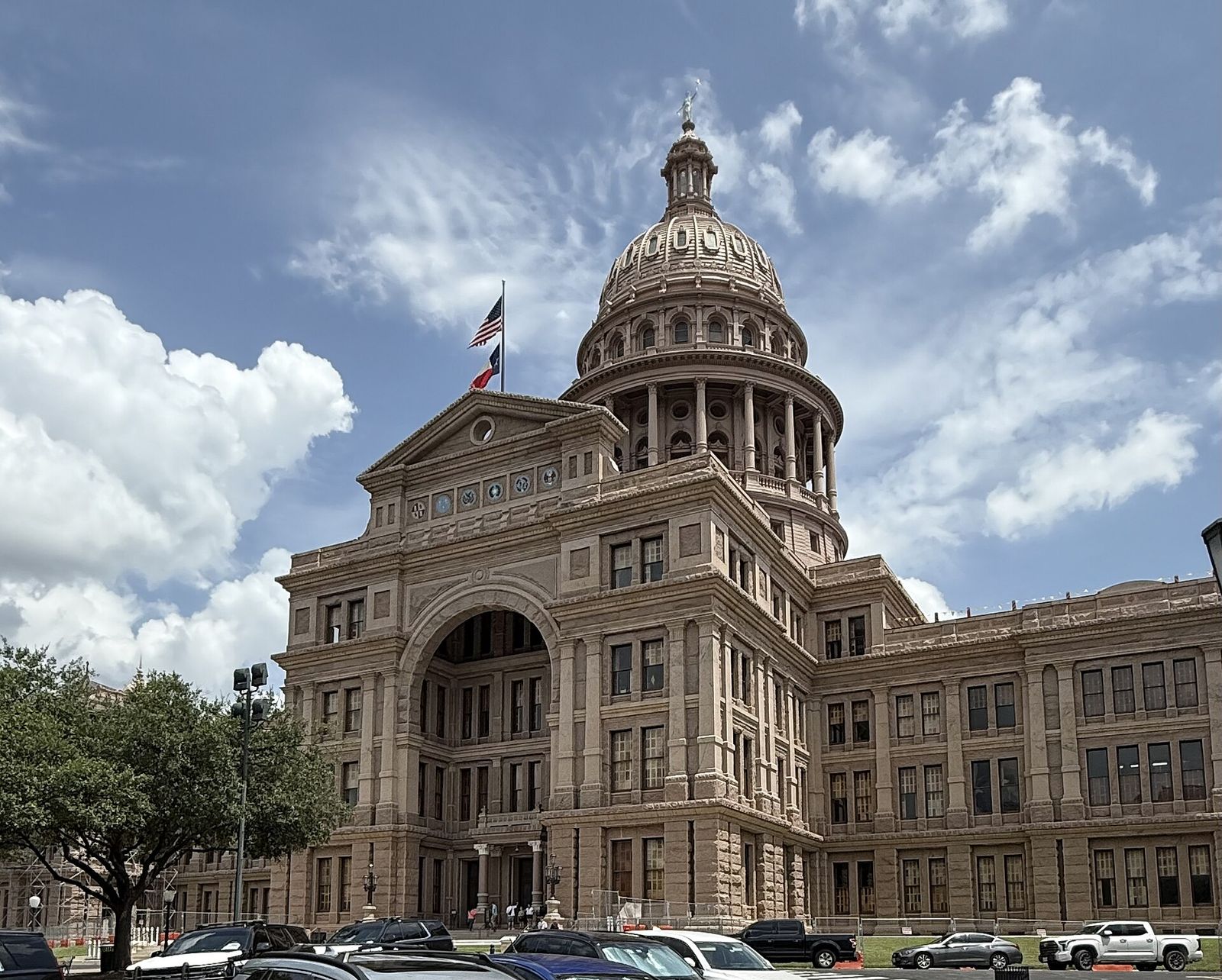 Pink granite dome of the Texas State Capitol in Austin rising above oak trees