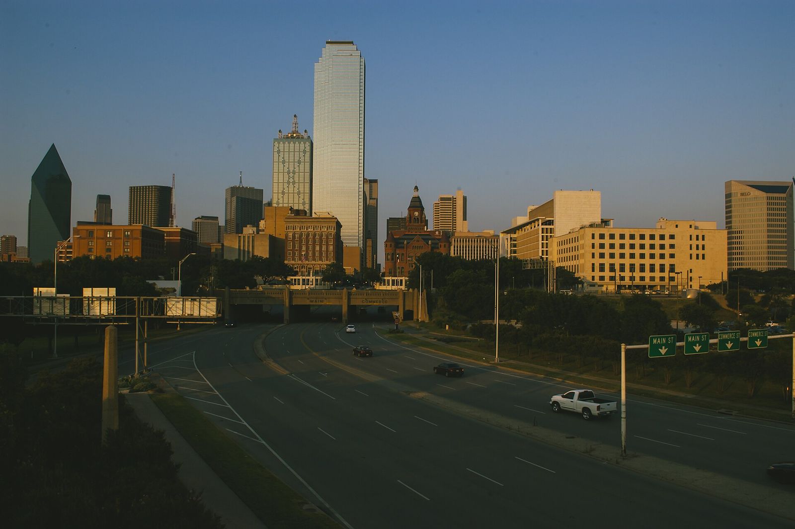 Downtown Dallas skyline lit by evening sun above a freeway