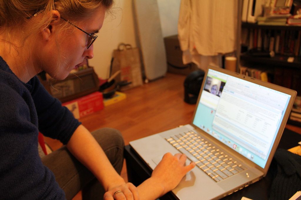 Woman typing on a laptop at a table in a warmly lit living room