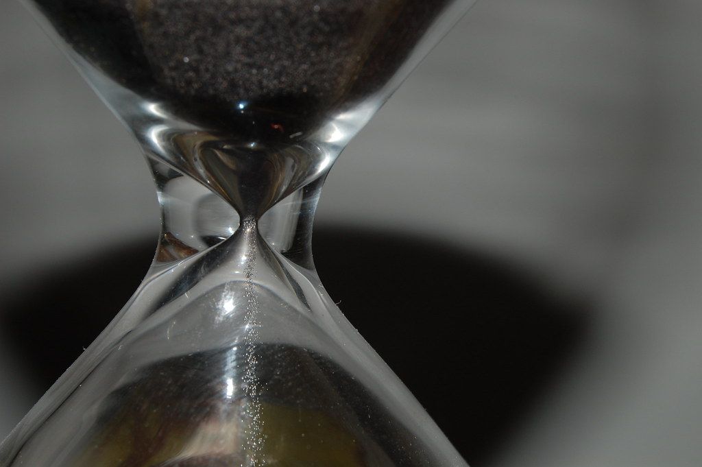 Close-up of sand falling through the narrow neck of an hourglass
