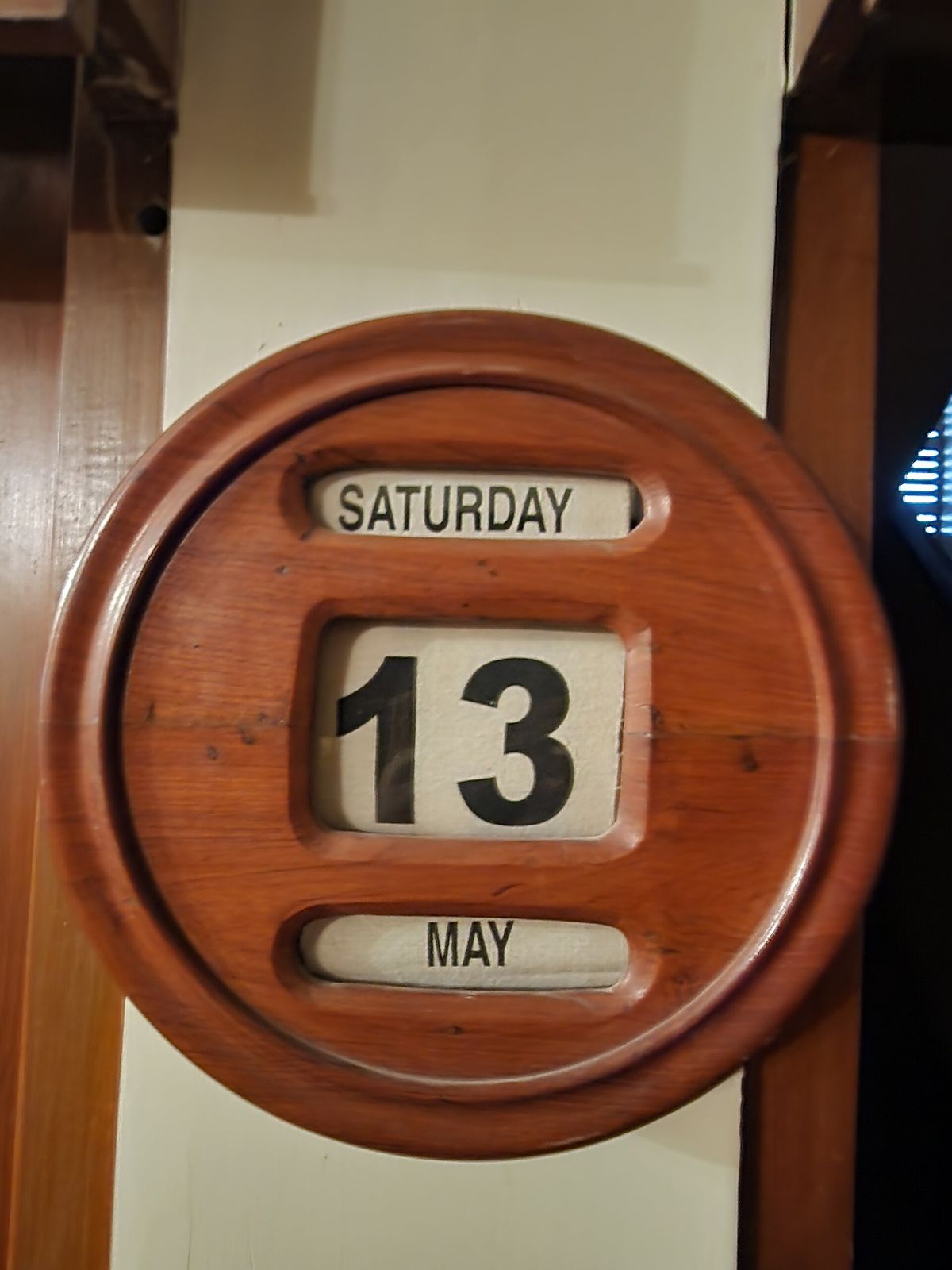 Round wooden wall calendar showing Saturday the 13th of May