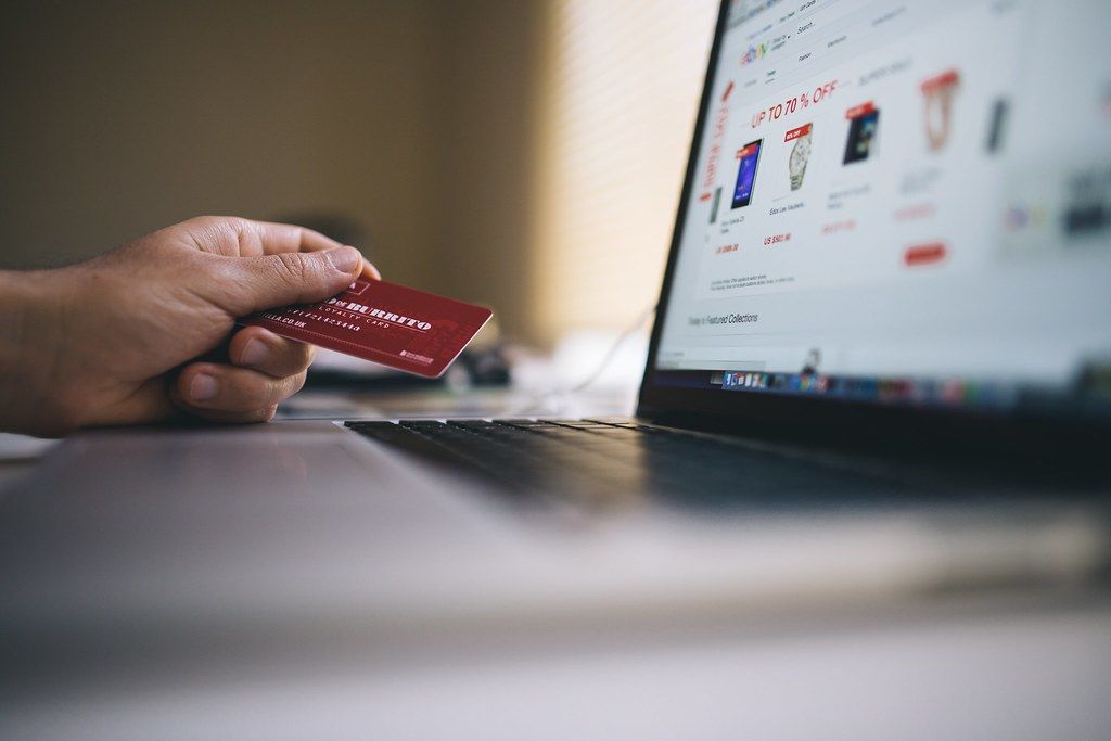 Hand holding a credit card beside a laptop during an online checkout