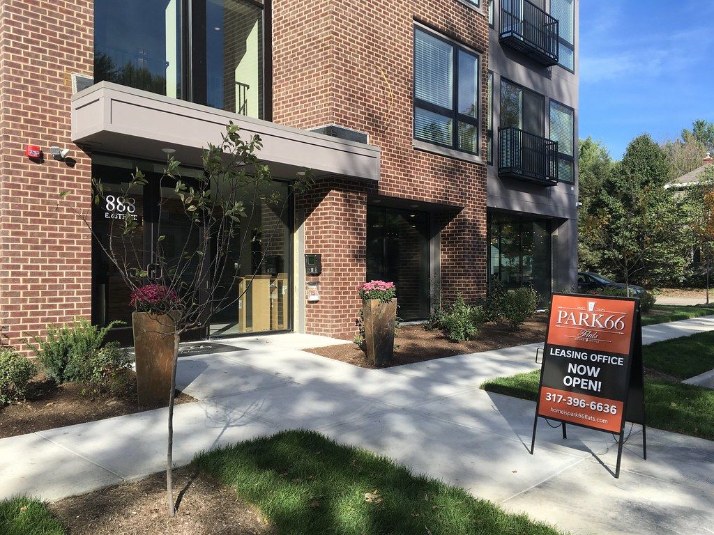 Leasing office now open sign outside a new brick apartment building