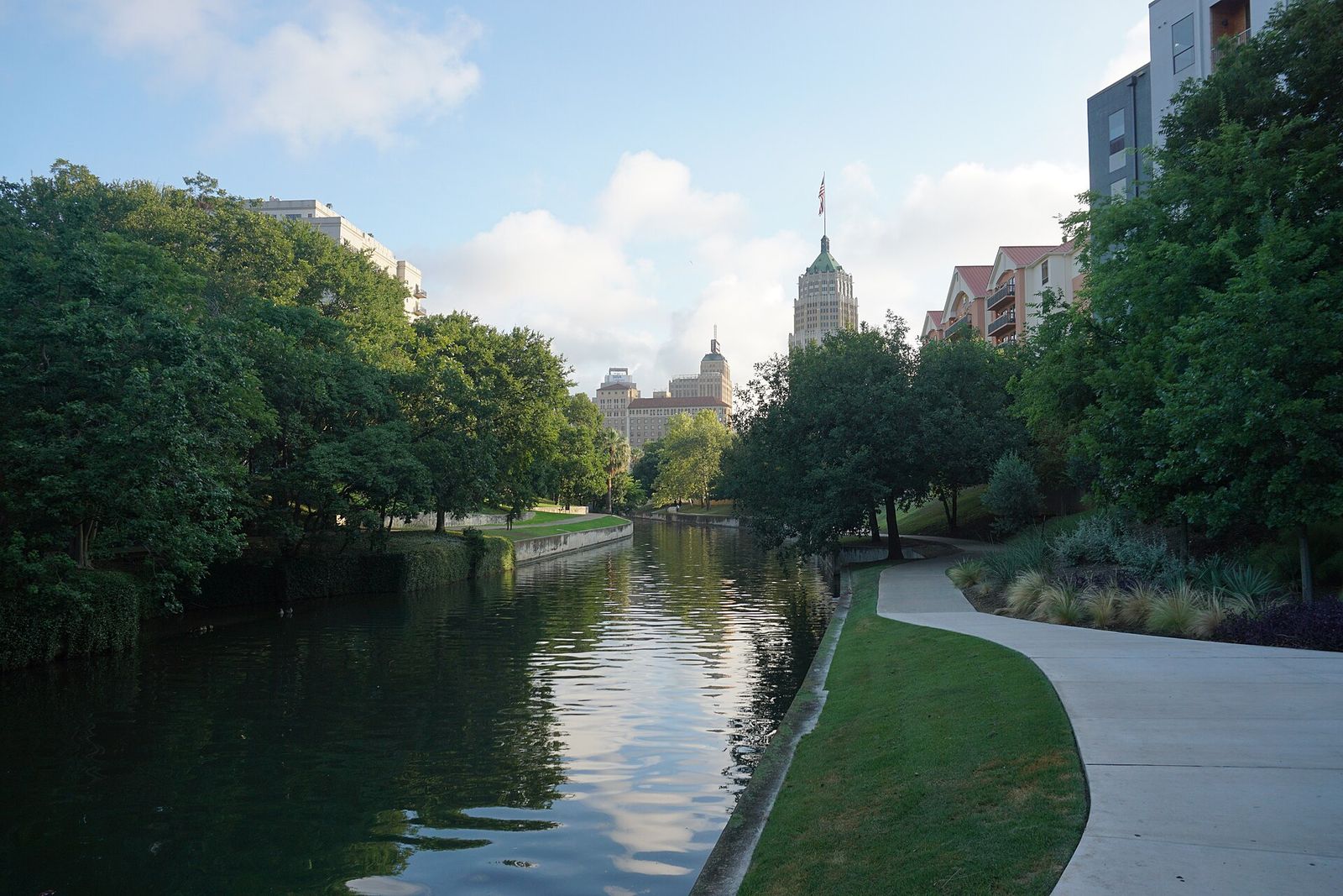 Quiet tree-lined stretch of the San Antonio River Walk with a curving path