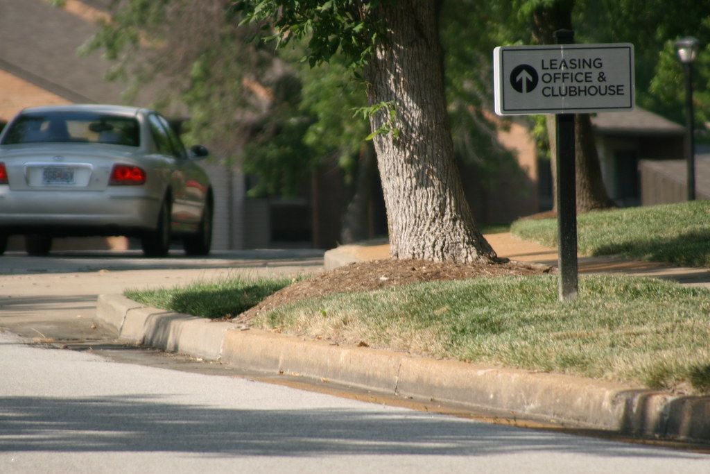 Roadside sign pointing toward an apartment leasing office and clubhouse