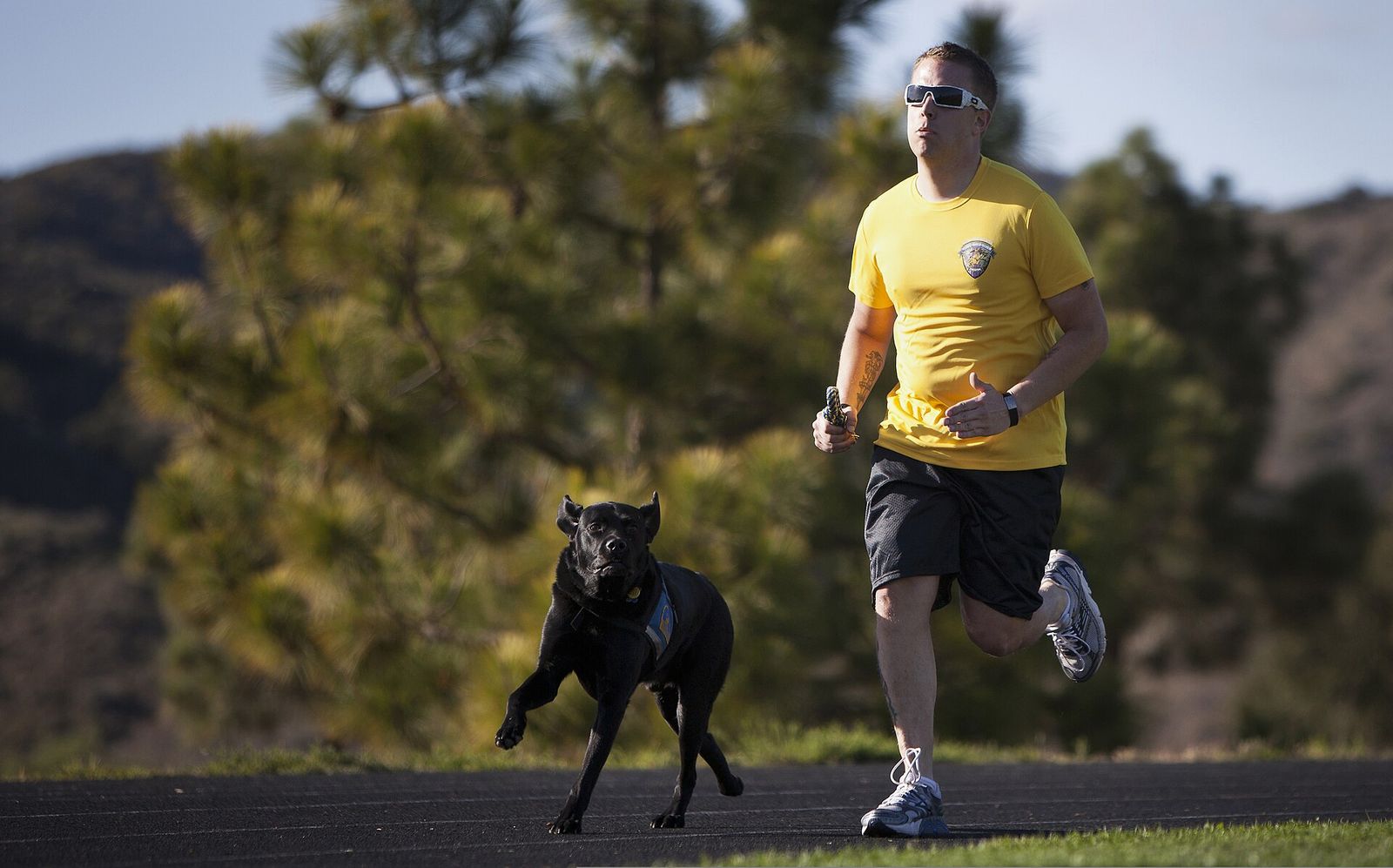 A veteran running outdoors alongside a black dog