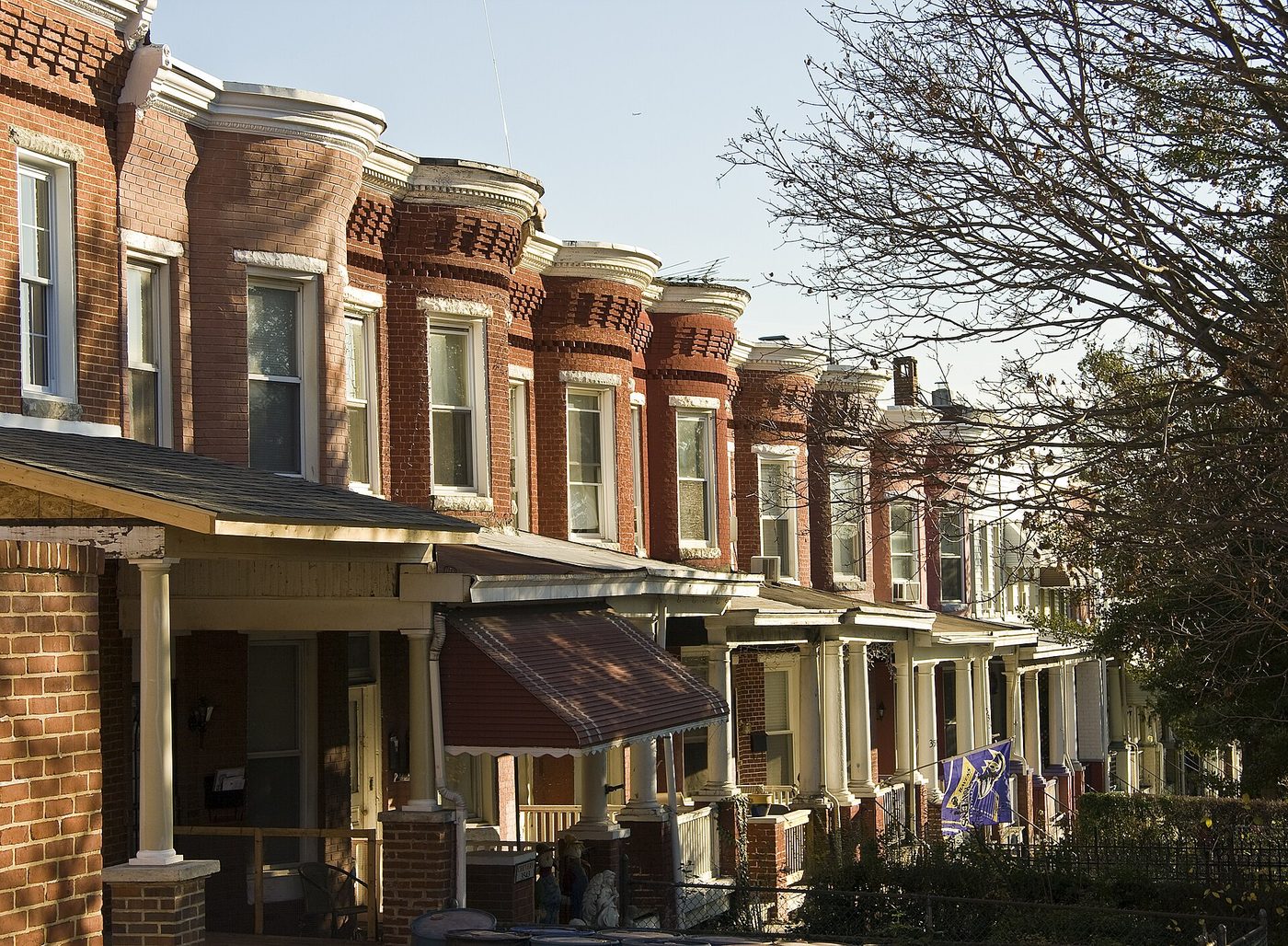 A row of Baltimore rowhouses with front porches and bay windows