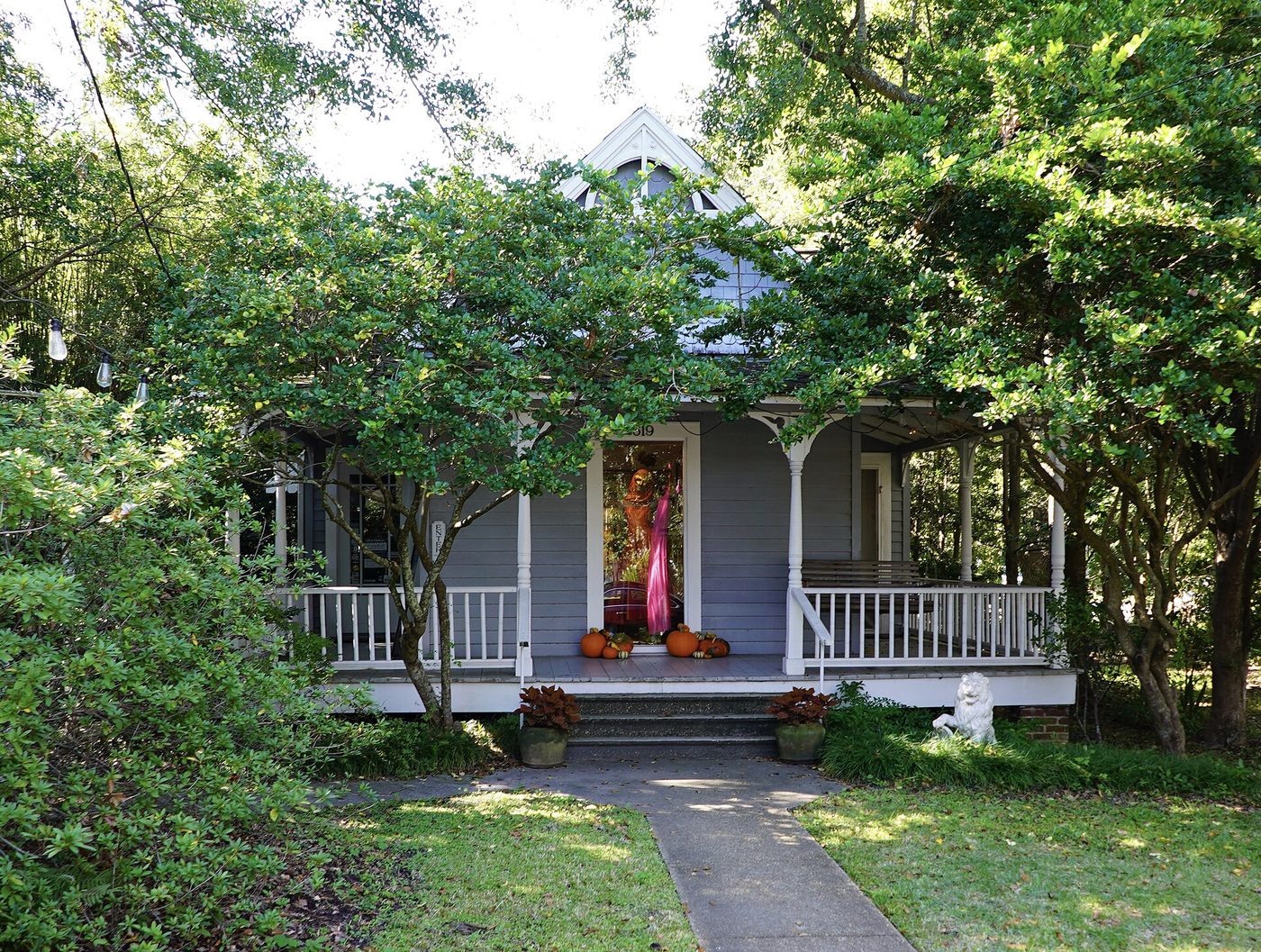 A wooden porch-fronted house shaded by mature trees in Mississippi