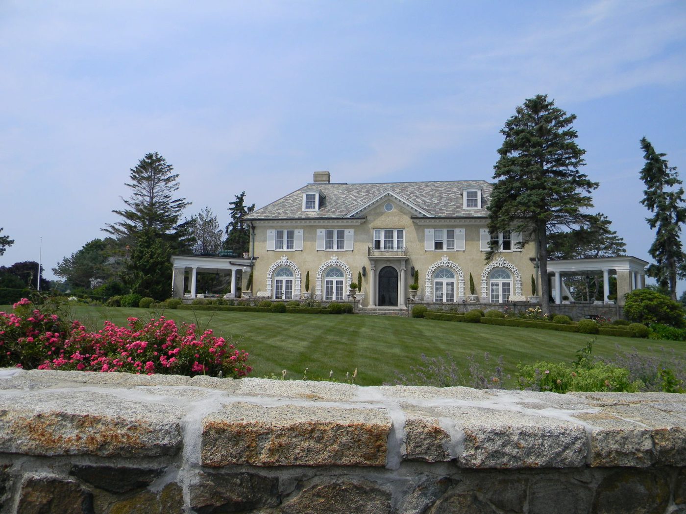 A large New Hampshire house set back behind a lawn and stone wall