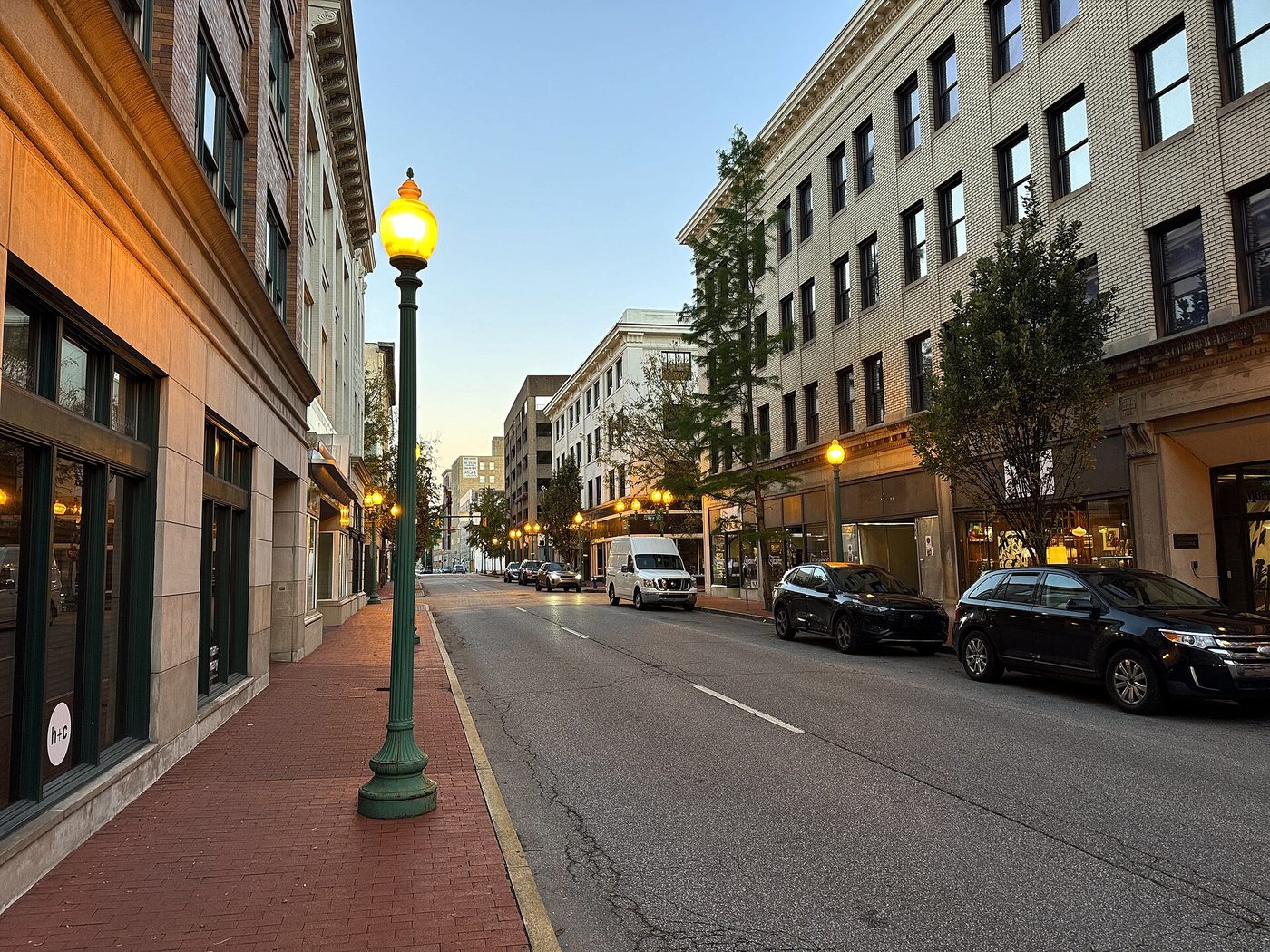 Quarrier Street in downtown Charleston at dusk, shopfronts under lit street lamps
